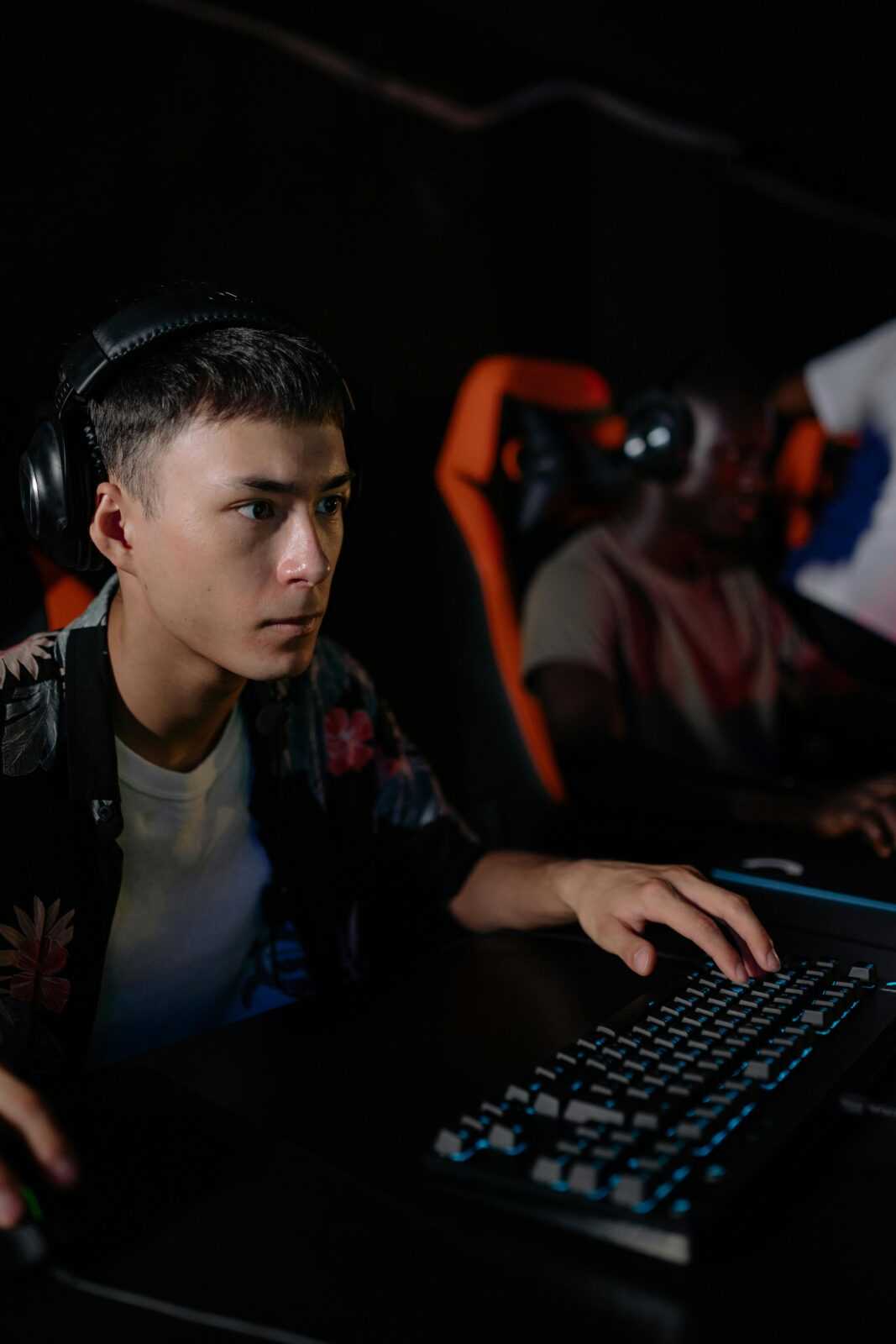 Teenagers engrossed in a competitive e-sports gaming session indoors with gaming setups.