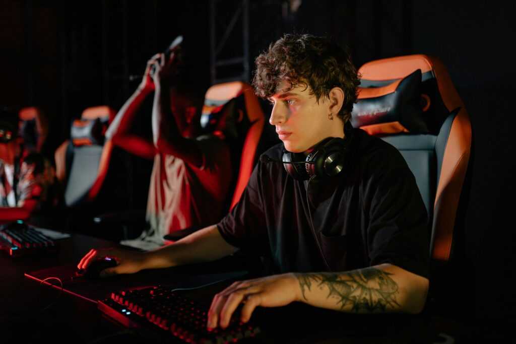 Competitive gamers in an esports tournament concentrating deeply in dimly lit setting.