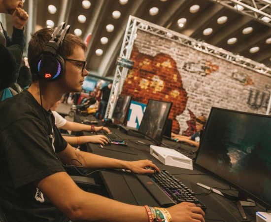 A young male gamer intensely focused during an esports event at an indoor gaming convention.