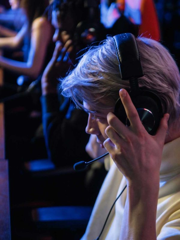 A young adult immersed in a gaming tournament, wearing a headset and focusing intently on the screen.