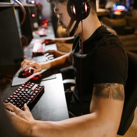 A gamer wearing headphones intensely focused on gaming in a cyber-themed arcade.